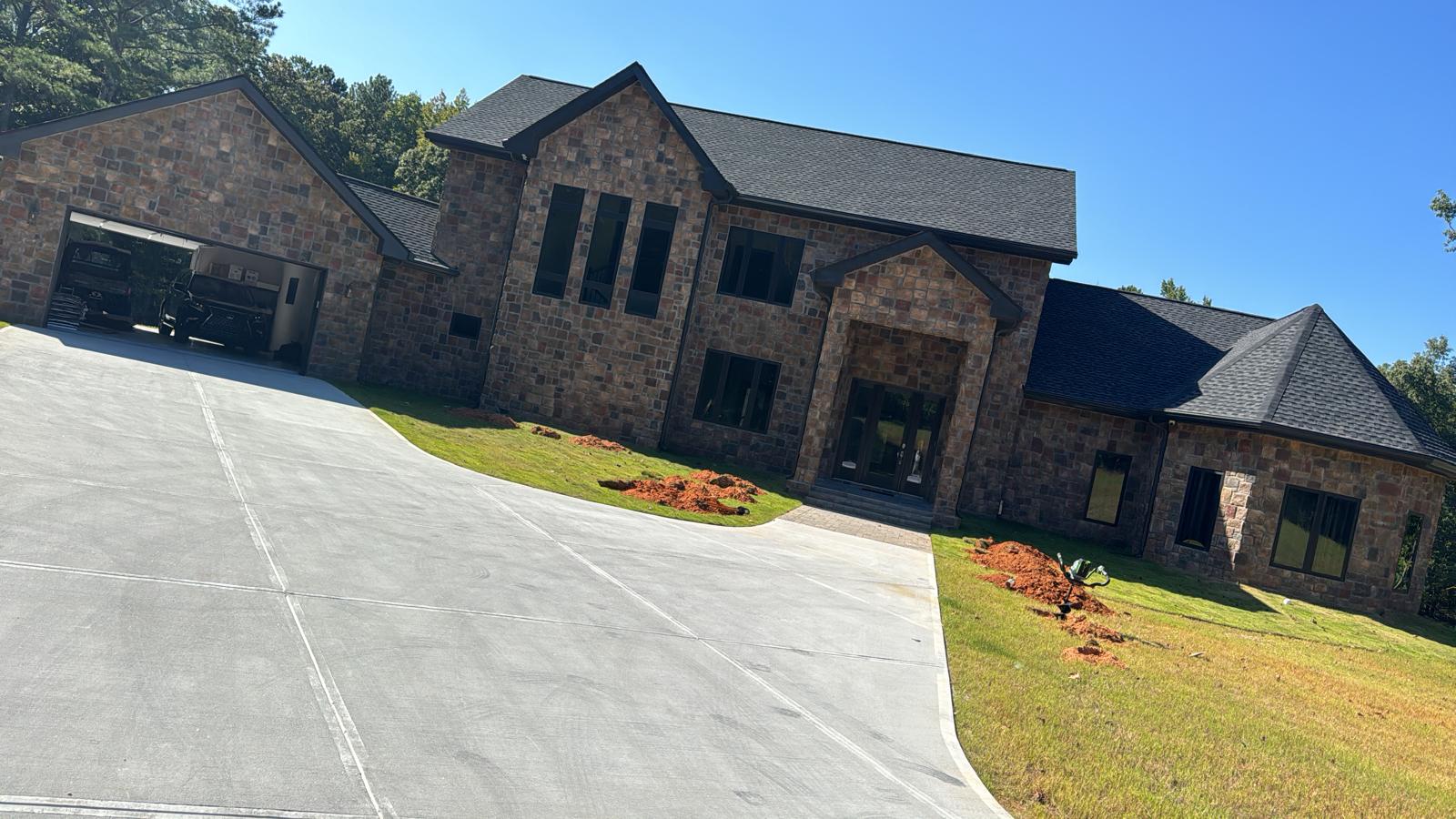 Long concrete driveway leading to a stone home